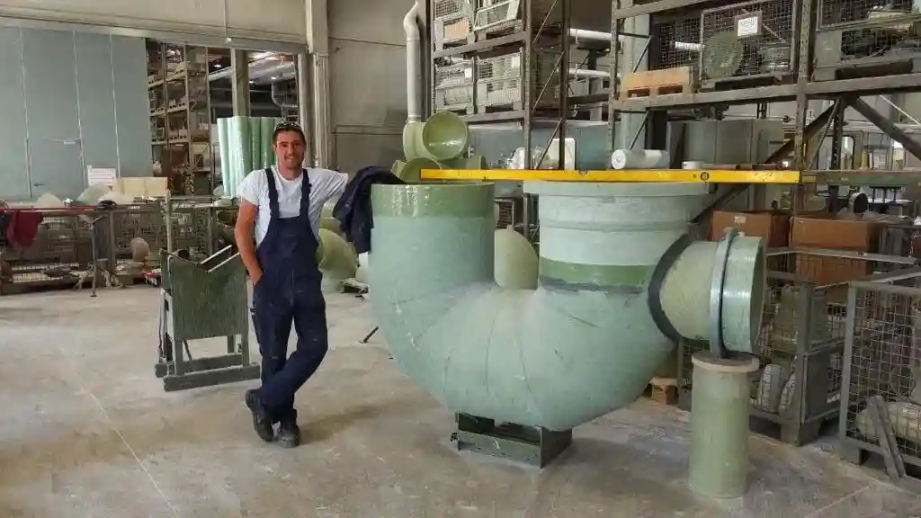 Worker beside a large fabricated composite pipe fitting
